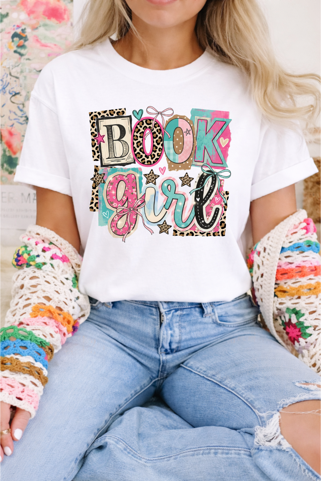 Person wearing a white t-shirt with 'Book Girl' design, sitting on a colorful surface.