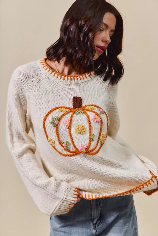 Woman wearing a sweater with a pumpkin design on a beige background