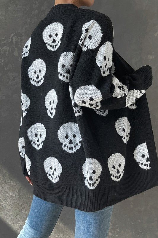 Black cardigan with white skull pattern worn by a person against a gray background