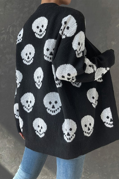 Black cardigan with white skull pattern worn by a person against a gray background