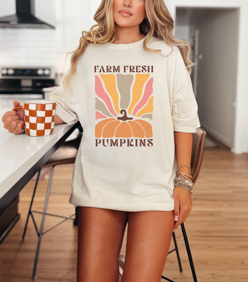 Woman wearing a 'Farm Fresh Pumpkins' shirt in a kitchen.