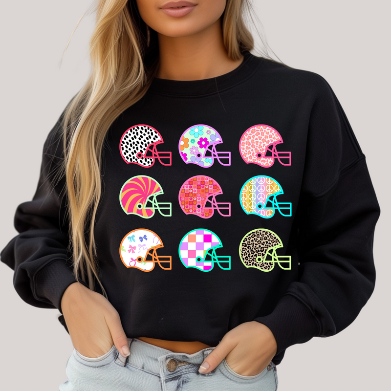 Black sweatshirt with colorful helmet designs worn by a person on a plain background