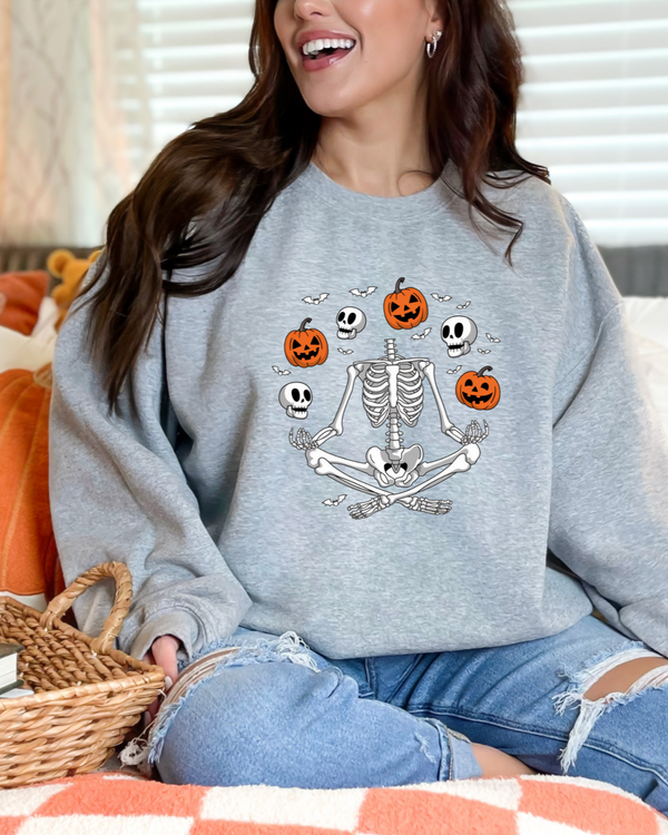 Person wearing a gray sweatshirt with Halloween-themed design, sitting on a couch with pumpkins in the background.
