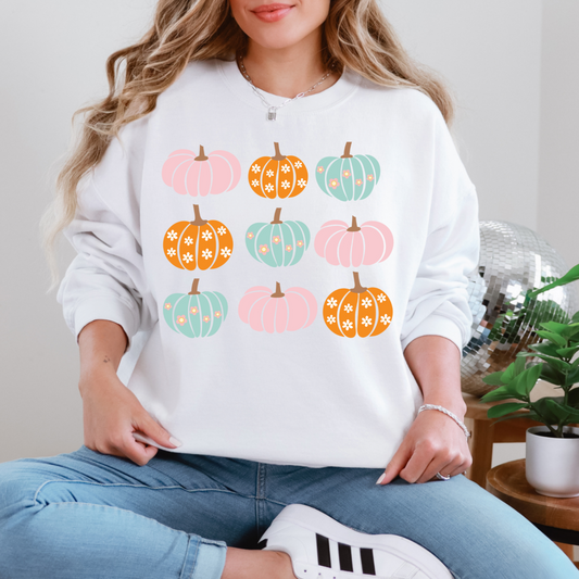 Person wearing a white sweatshirt with colorful pumpkin patterns, sitting indoors.