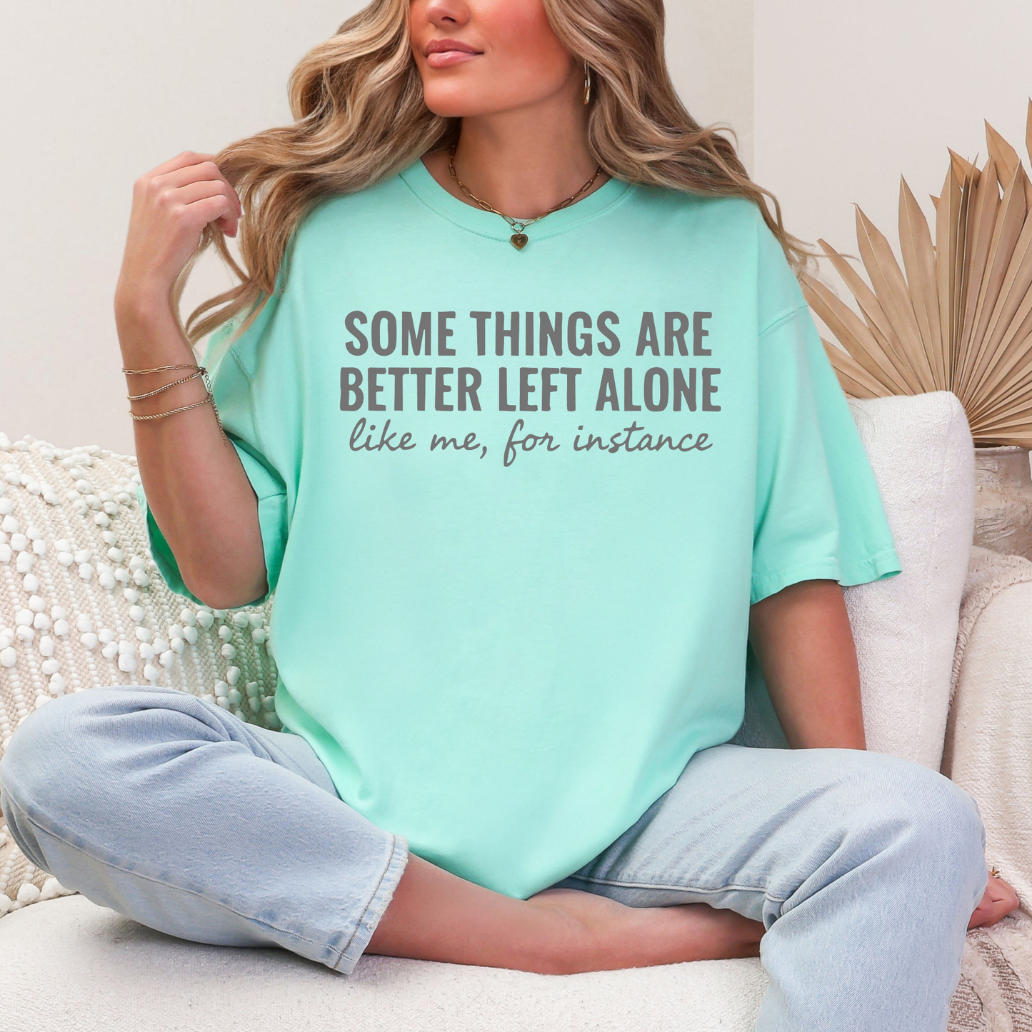 Person wearing a light blue t-shirt with text, sitting on a couch.