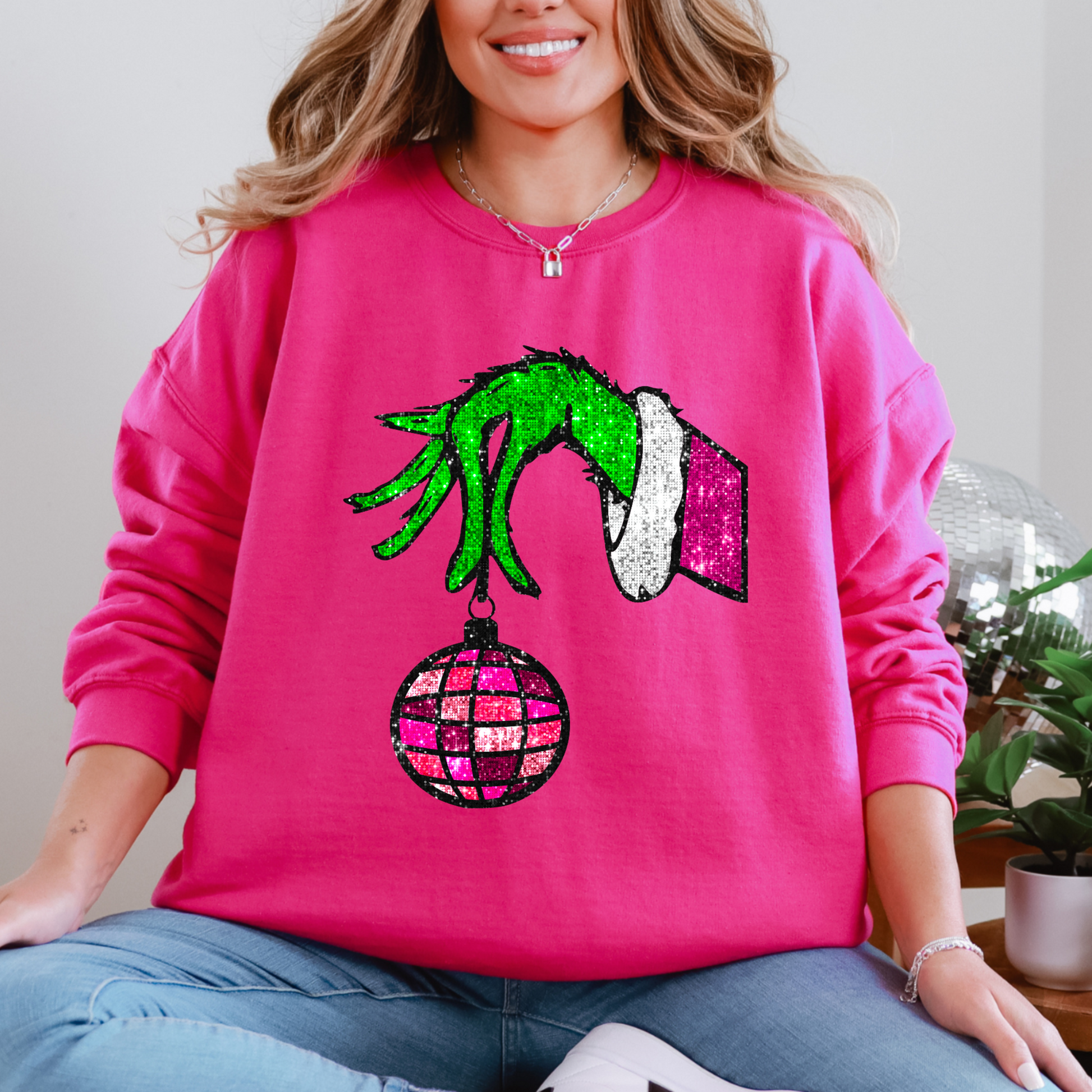 Person wearing a pink sweatshirt with a festive design, sitting indoors.